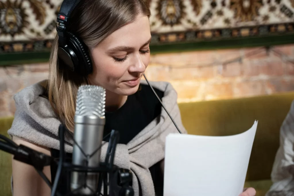 Mulher usando fones de ouvido e microfone enquanto lê um roteiro para podcast