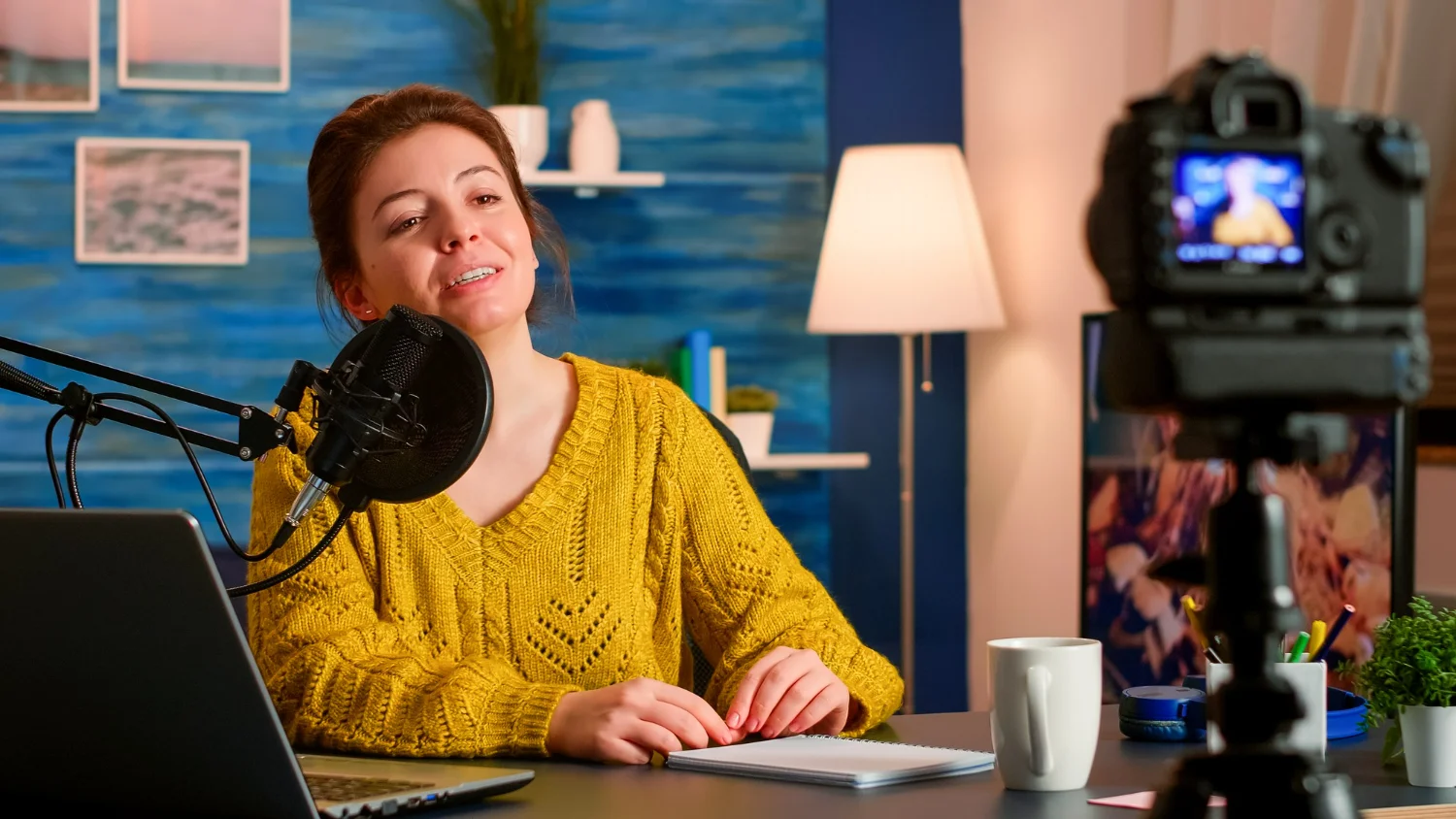 Mulher gravando vídeo com câmera no tripé em um estúdio para divulgar podcast